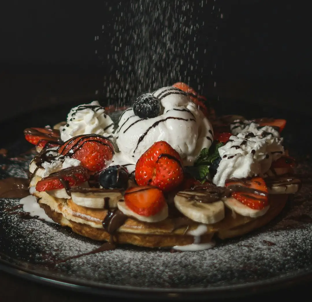 a waffle topped with whipped cream and fruit